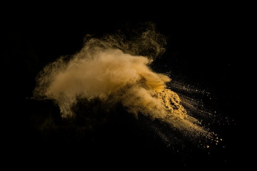 Golden powder explosion against black background photo