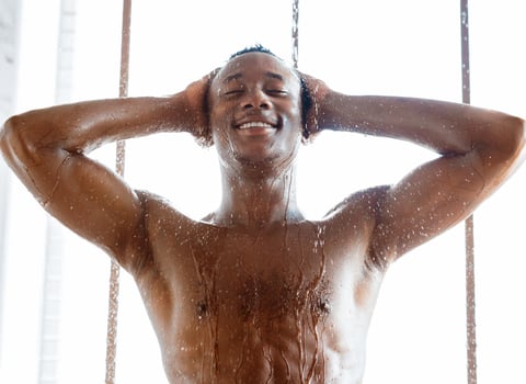 Happy African American Man Taking Morning Shower Washing Head Standing In Modern Bathroom Indoor, Enjoying Falling Refreshing Water Drops. Male Bodycare And Hygiene Concept. Vertical Shot photo