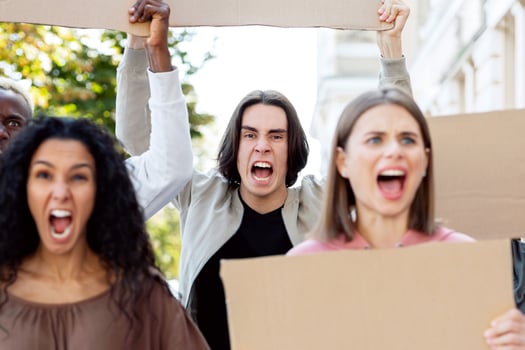 Closeup of furious multiracial millennial protestors with empty placards chanting slogands next to government building on the street, striking against 2021 lockdown restrictions, closeup photo