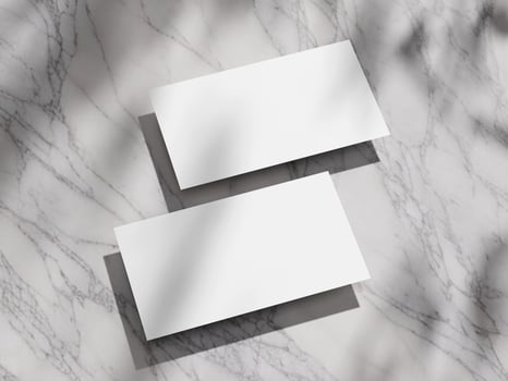 Clean, white business card mockup on a polished marble backdrop with natural light shadows. photo