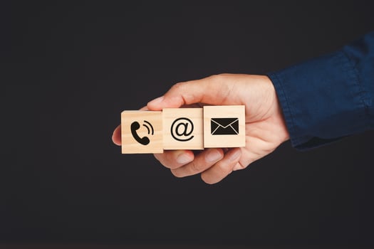 Customer service and contac us. Hand businesspeople holding wooden cubes with symbols of a mobile, address, and email against a black background photo