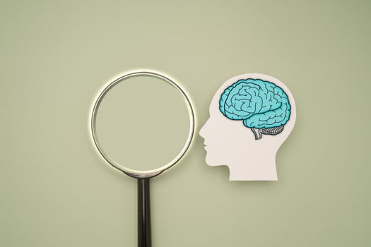 A brain shape symbol and a magnifying glass on a green background photo