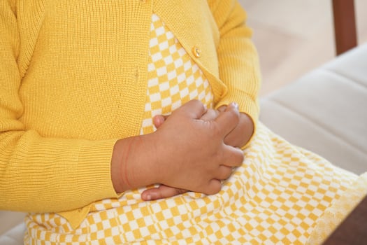 Child in yellow outfit suffering stomach pain photo