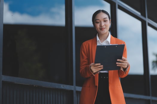 Asian business woman holding a clipboard and looking at a computer screen photo