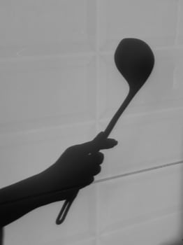 Shadow of a hand holding a ladle against a textured backdrop photo