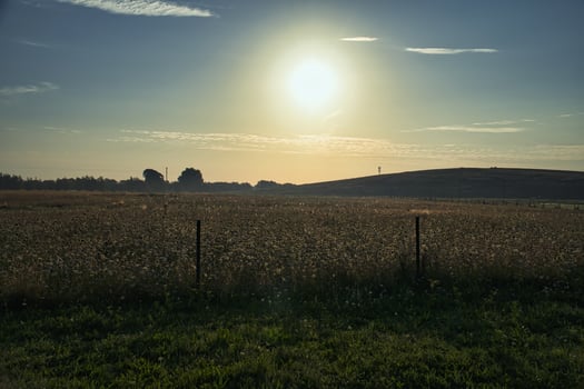 Sunset over a wide field with rolling hills in background photo
