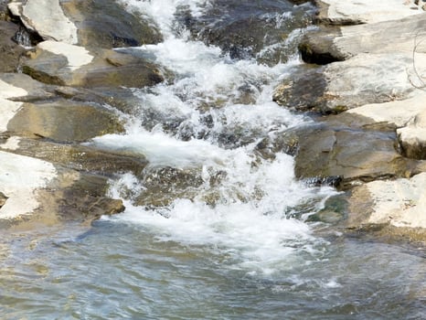 Serene mountain stream cascading over rocks in natural landscape photo