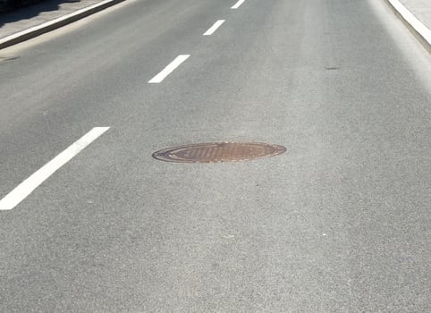 Empty road with manhole cover on asphalt surface photo