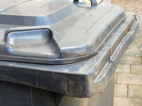 Large outdoor garbage bin with lid on urban street pavement photo