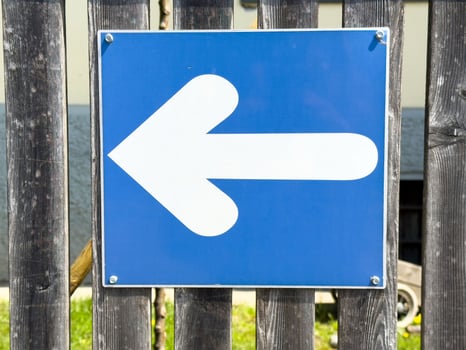Blue left arrow traffic sign on wooden fence background photo