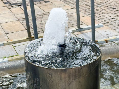Close-up of modern urban water fountain bubbling on stone pavement photo