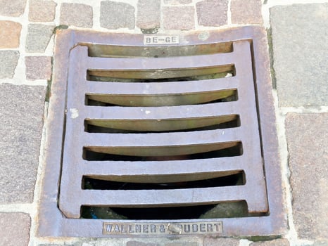 Metal grate on cobblestone street with iron bars and drainage photo