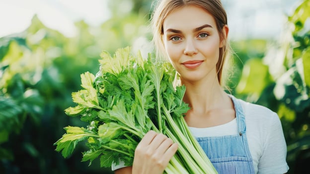 Young woman holds fresh celery in a vibrant green garden during daytime photo