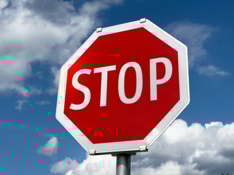 Bright red stop sign against blue sky and clouds photo