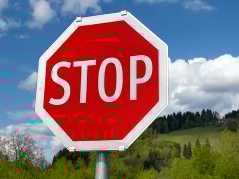Stop sign in scenic green landscape with blue sky and clouds photo