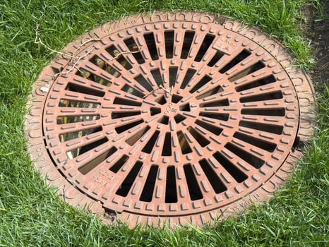 Round iron manhole cover on grass surface in urban environment photo
