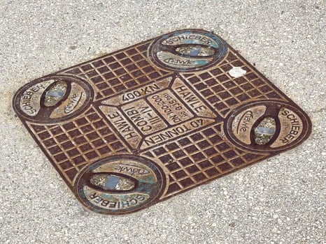 Rectangular metal manhole cover on concrete surface with brand names photo