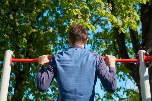 Man doing pull-ups on outdoor horizontal bar photo