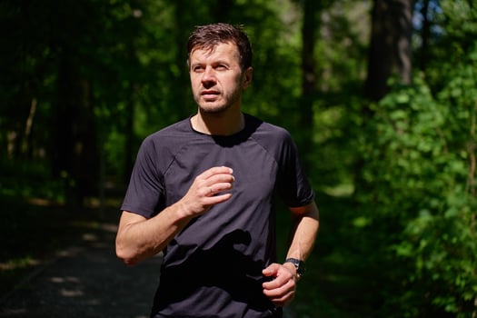 Man running on forest trail in summer morning photo