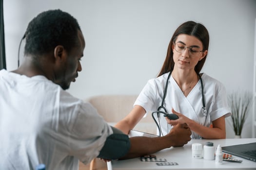 Sitting, by a table. Female, doctor measures blood pressure of a man photo