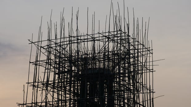A silhouette of construction site with scaffolding against sunset sky, showcasing intricate structure of framework. scene evokes sense of progress and development photo