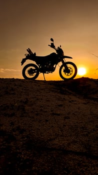 Silhouette of a Motorcycle Against a Vibrant Sunset on a Hilltop Capturing Adventure and Freedom in the Great Outdoors photo