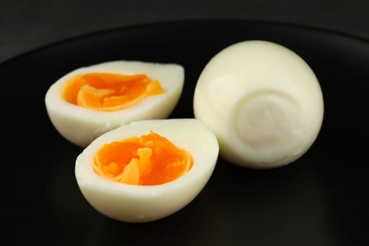 Soft boiled eggs served on a black plate with a rich orange yolk and smooth white exterior photo