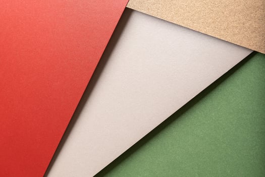 Paper background with matte texture. Layered diagonal sheets in bright red, champagne, metallic photo