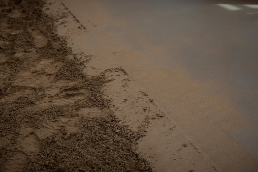 Close up view of a construction site floor showing underfloor heating pipes being installed and covered with screed concrete, partially smoothed. photo