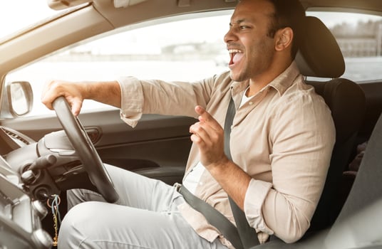 Road Trip Playlist. Joyful Indian Driver Man Singing While Driving His New Car, Enjoying Favorite Music And Fast Ride Sitting In Auto. Joy Of Automobile Ownership Concept. Side View Shot photo