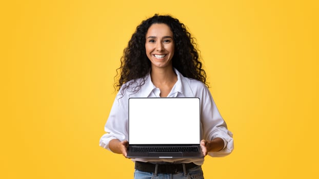 Check This Website. Happy Woman Holding Laptop Computer With Black Blank Screen, Isolated Over Yellow Background, Mockup Image With Copy Space, Template For Your Design, Free Place For Advertisement photo