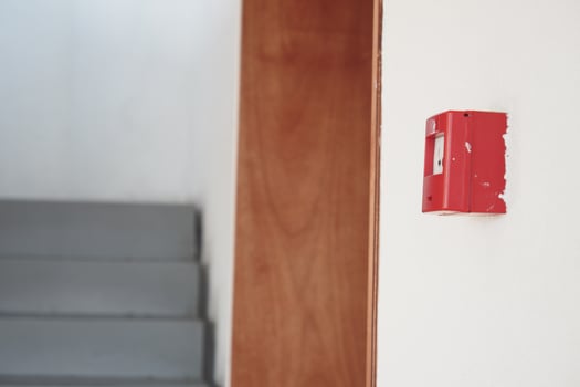 Fire alarm mounted on wall near staircase in indoor building setting photo