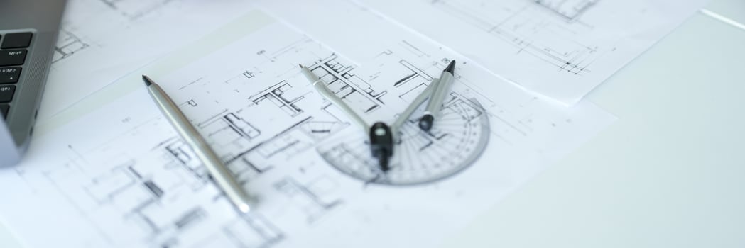 a laptop computer and a pencil on top of blueprints photo