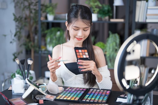 a woman is holding a makeup palette and looking at it live streaming photo
