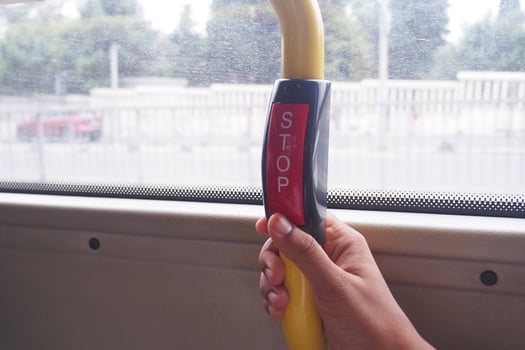 Hand presses stop button on bus while commuting in city photo