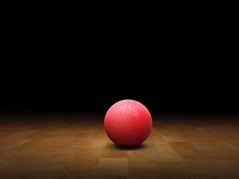 Classic red dodgeball ball, rubber ball on wooden floor, black background. photo