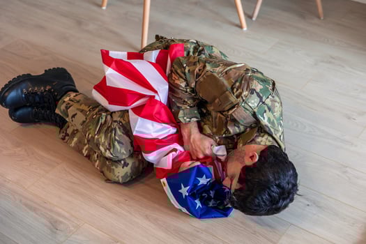 American soldier suffering from post-traumatic stress disorder hugging United States flag on the floor photo