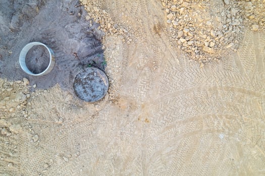 overhead drone view of a construction area with manhole and concrete ring, top-down aerial view of a construction site detail photo