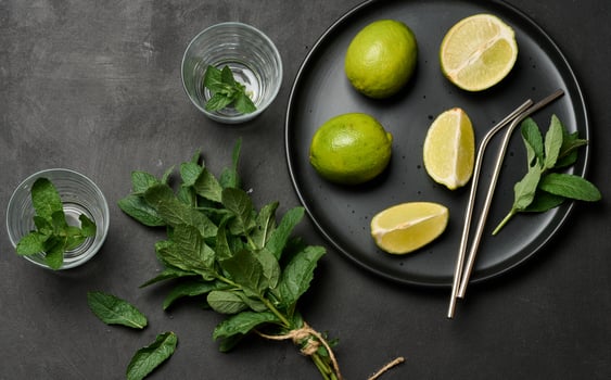 Bunch of fresh green mint, lime slices, glasses, top view. Cocktail ingredient. photo