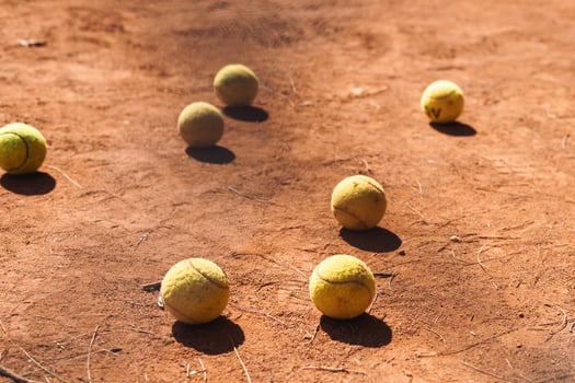 Tennis balls scattered on clay court during a sunny afternoon practice session photo
