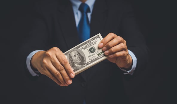 A businessman holding US dollar bills while standing on a black background. photo