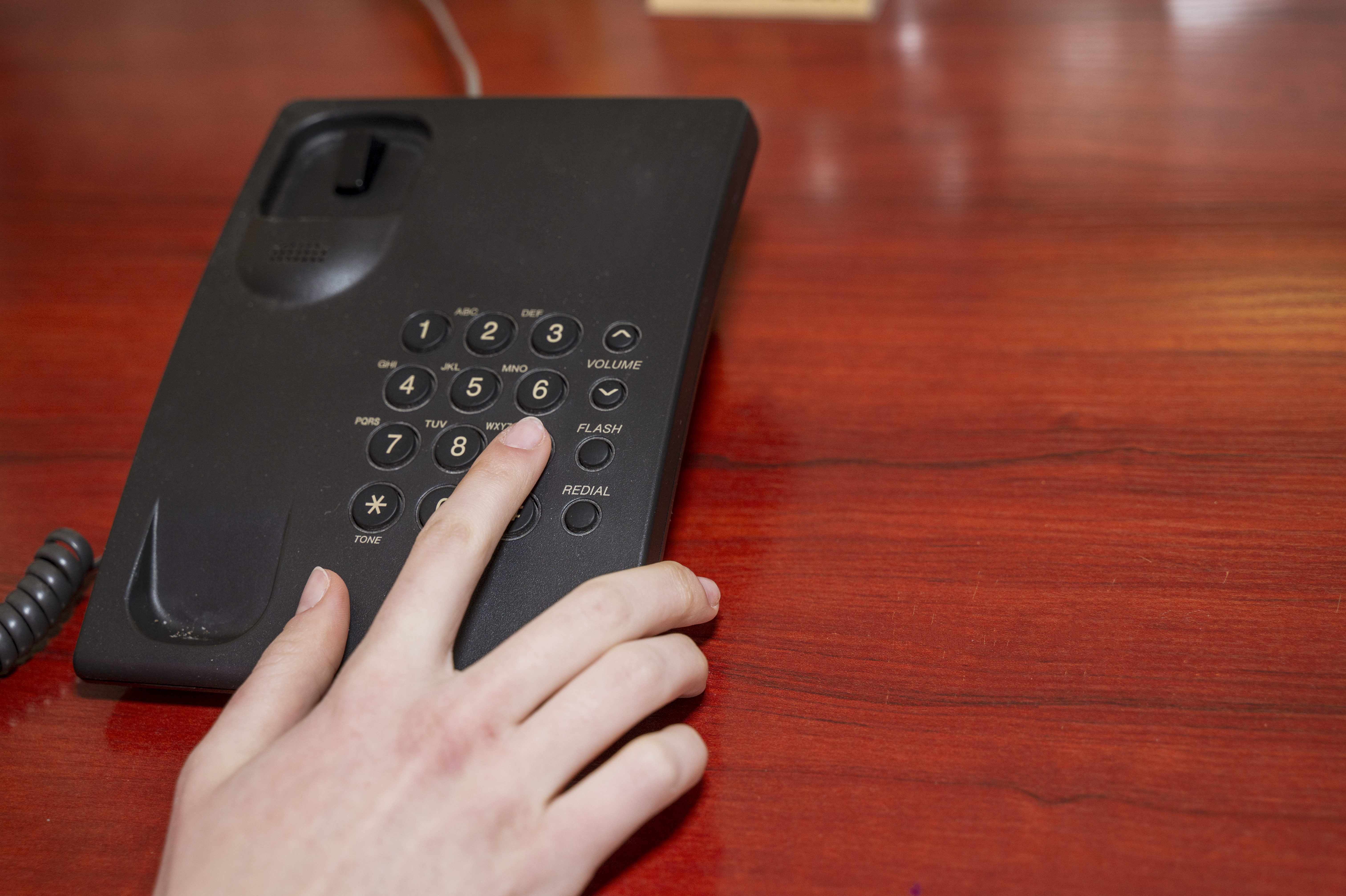 close up woman hand pointing try to press button number on telephone office desk. High quality photo