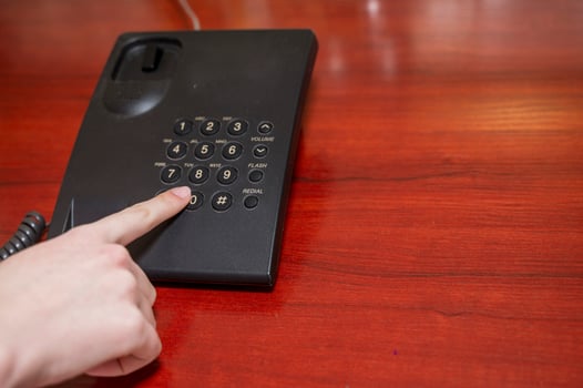 Woman's finger pressing a key on a telephone. Hand dialing a telephone number with the headset raised photo