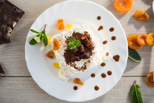 sweet breakfast in a plate with cottage cheese in chocolate syrup with candied fruits photo