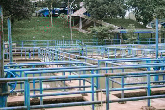Wastewater Treatment Plant with Blue Handrails and Greenery Backdrop photo