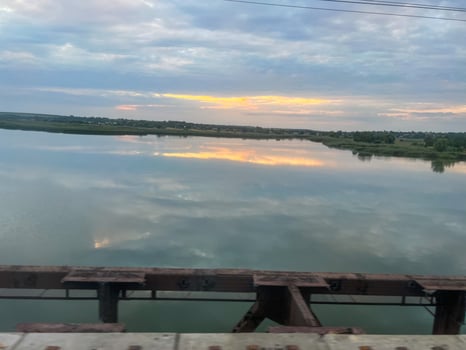 Train crossing river at sunset reflecting cloudy sky photo