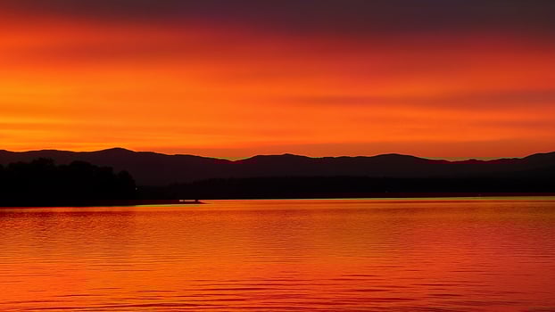 Vivid Orange Sunset Over Calm Lake Water photo