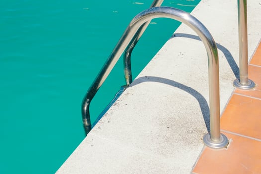 detail of a swimming pool edge ladder and water photo