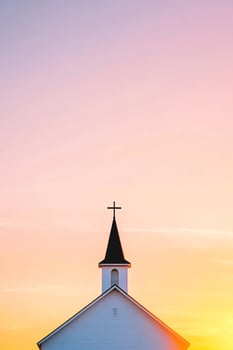 Sunset behind church steeple with cross against colorful sky. photo