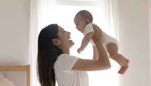 East Asian mom cuddling baby in calm morning nursery photo